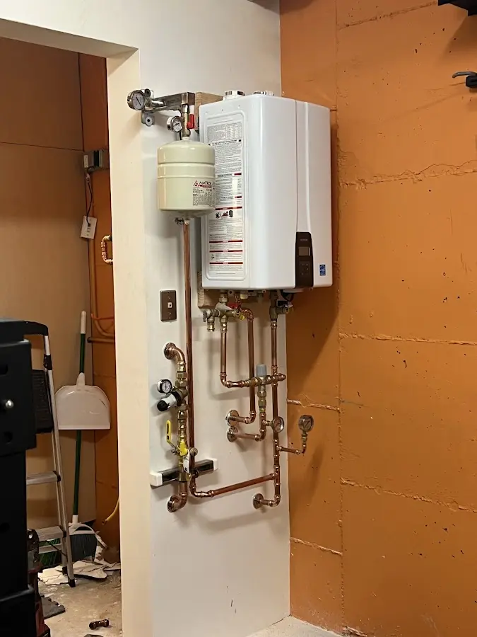 Plumbing technician inspecting water heater connections in Landmark